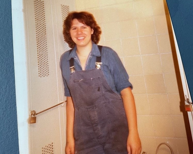Claudia im Blaumann an einen Metallsoind gelehnt