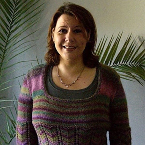 Claudia vor einen Palme im Wohnzimmer mit einem Pulli im Farbverlauf in Rosa bis Braun