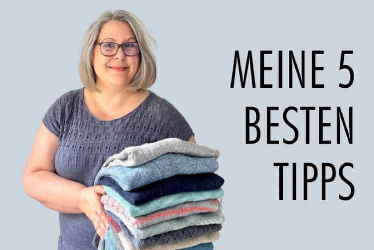 Claudia mit einem Stapel handgestrickte Oberteile im Arm