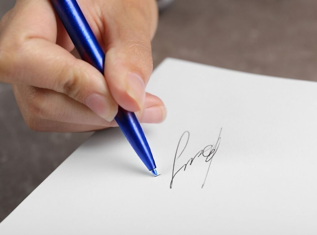 Foto einer Hand, die ein Buch signiert